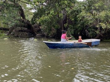People sitting on boat against trees