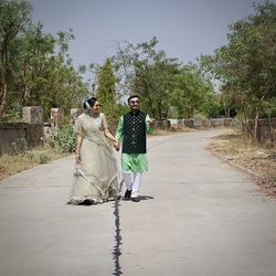 Rear view of people walking on road amidst trees