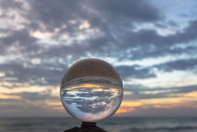 Close-up of crystal ball against sky during sunset