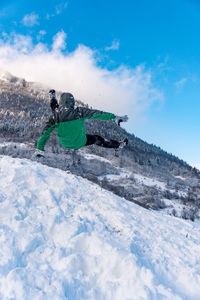 Rear view of person falling on snowcapped mountain against sky