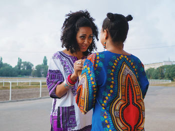 Young female friends standing at race course against sky