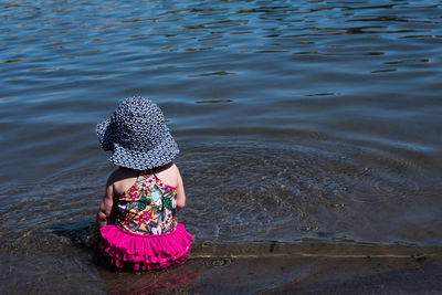 Rear view of woman sitting in sea