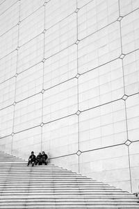 People sitting on staircase against wall