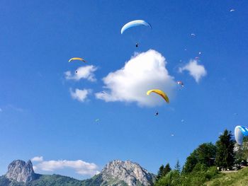 Low angle view of paragliding against blue sky