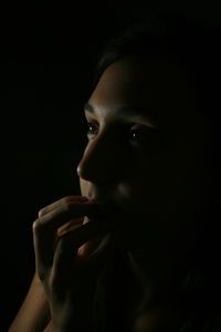 Close-up of young woman against black background