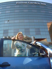 Portrait of young woman on car in city