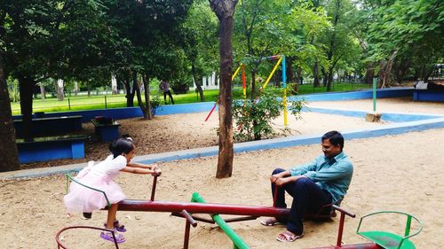 Father and daughter playing on seesaw at park