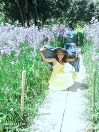 Portrait of smiling woman standing by flowering plants