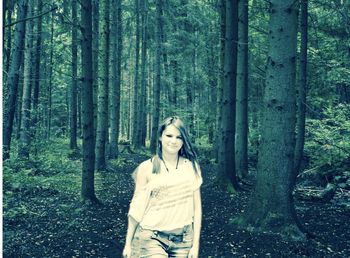 Portrait of young woman standing on tree trunk in forest