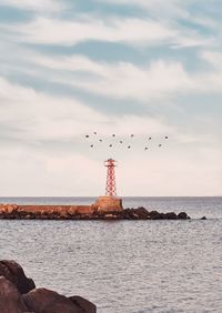 Birds flying over sea against sky