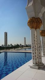 Swimming pool by building against clear blue sky