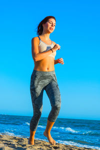 Full length of woman standing on beach against clear blue sky