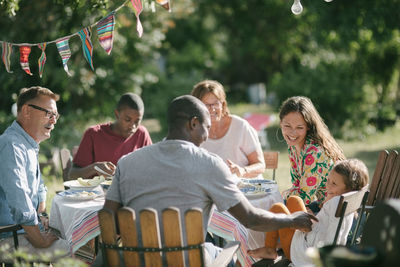 Happy multi-generation family having lunch together in backyard during garden party