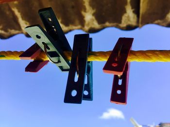 Low angle view of clothespins hanging on clothesline against sky