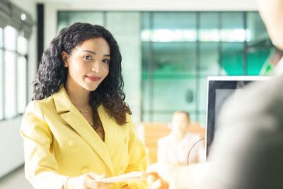 At the airport check-in counter, a passenger hands over his documents to the manager via a counter 