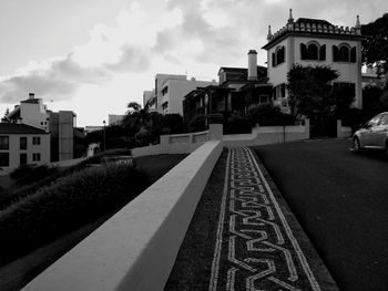 Empty road by buildings against sky in city