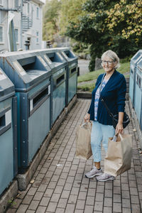 Woman with paper bags at recycling bins