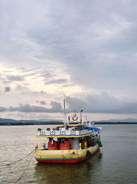 Fishing boat moored in sea against sky