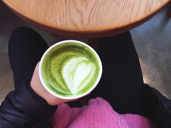 Close-up of hand holding matcha tea at table