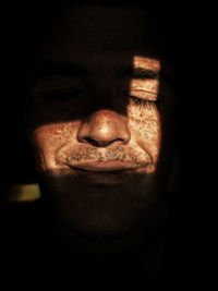 Close-up portrait of man against black background