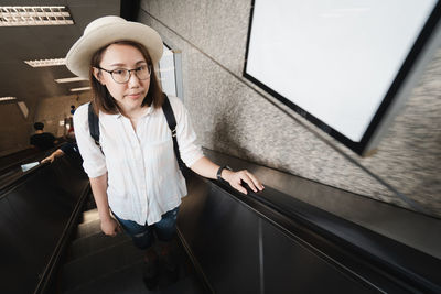 Portrait of woman standing on escalator 