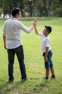 Full length of father and son standing on field