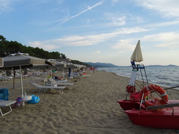 Deck chairs on beach against sky