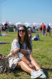 Young woman wearing sunglasses sitting on field