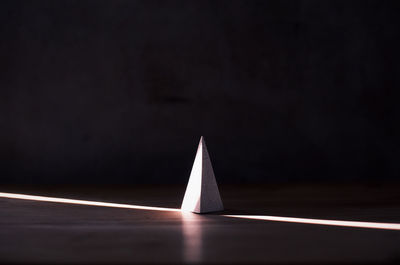 Close-up of light bulb on table against black background