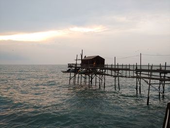 Lifeguard hut by sea against sky during sunset