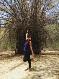 Full length of woman standing by bare tree