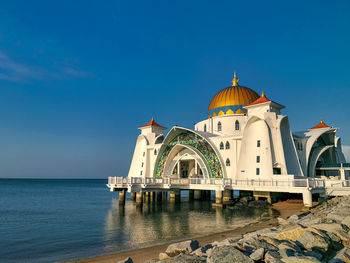 View of building by sea against blue sky