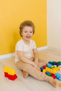Cheerful happy kid is playing with toys. a boy builds a construction kit at home spending time