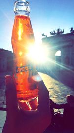 Close-up of hand holding bottle by sea against sky