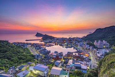 High angle view of townscape by sea against sky during sunset