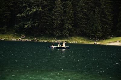 People on lake against trees in forest