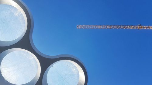 Low angle view of crane and huge ceiling against clear blue sky