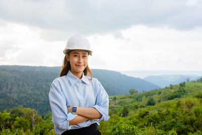 Portrait of young woman standing against sky