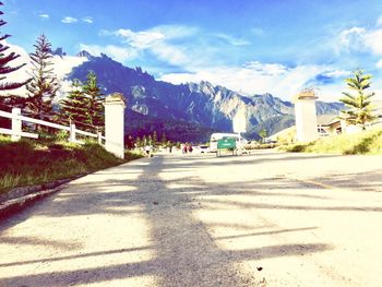 Road by trees and mountains against sky