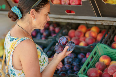 Mature woman choosing fruit in street store