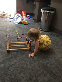 Cute girl playing with toy while sitting on floor