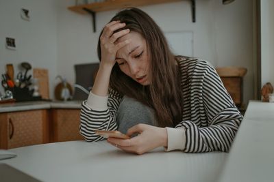 Side view of young woman sitting on sofa at home