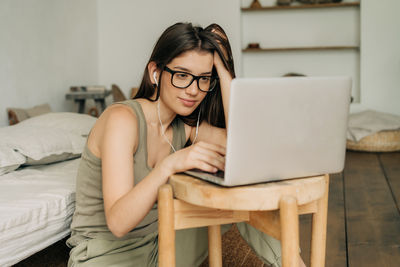 A young woman is using a laptop to work from home.