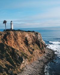 Lighthouse by sea against sky