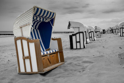 Hooded chairs on beach against sky