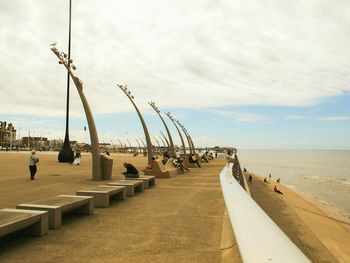 People on promenade against cloudy sky