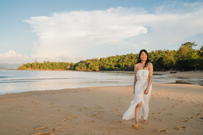 Full length portrait of young woman on beach