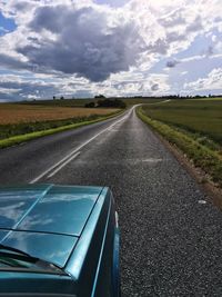 Car on country road against cloudy sky