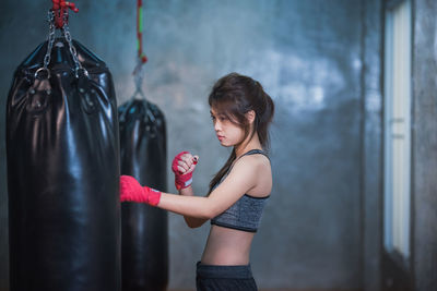 Side view of female boxer punching bag