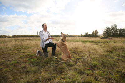 Man playing with dog on land against sky